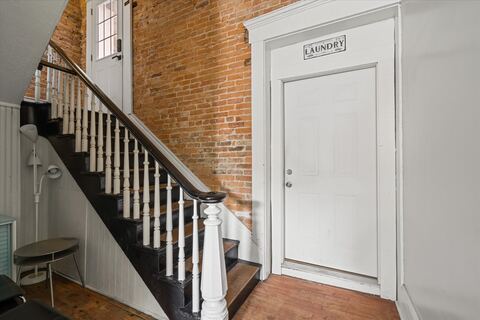 Staircase with exposed brick beside the laundry room